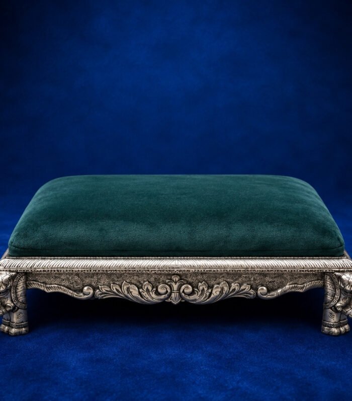 Handcrafted 999 silver sheeting pooja stool with ornate elephant legs and emerald green velvet.